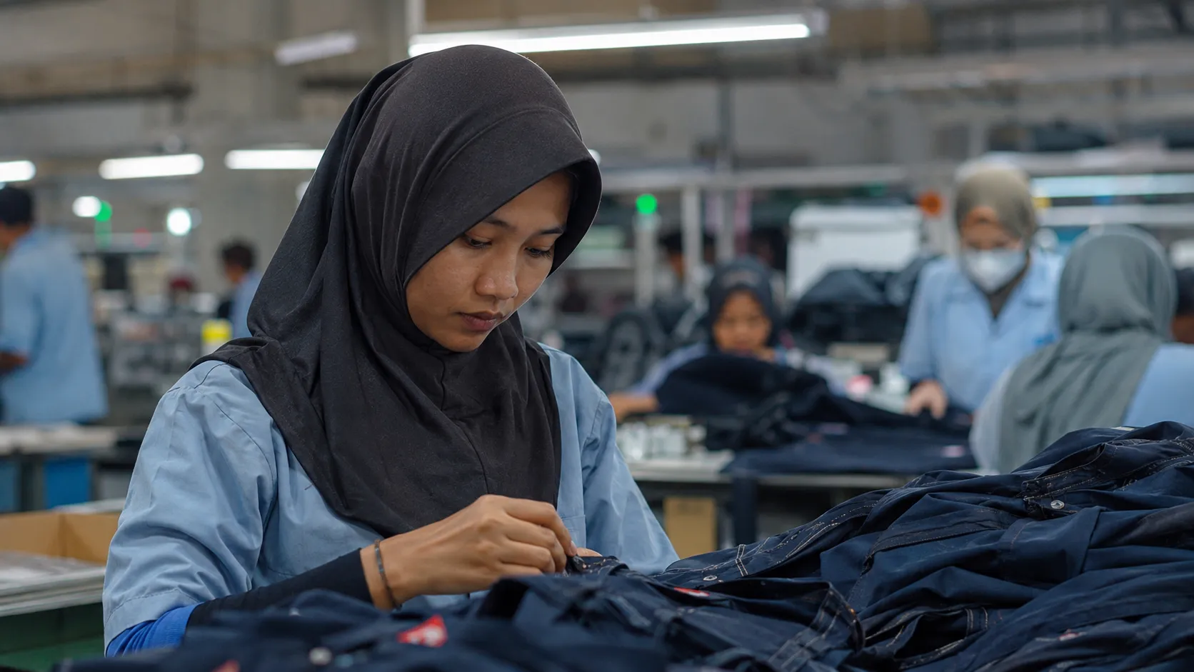 A female Indonesian factory worker in a hijab inspecting export goods affected by the US Tariffs Indonesia